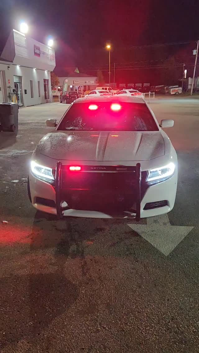 Voiture de police Dodge Charger blanche avec strobes et gyrophares en action la nuit